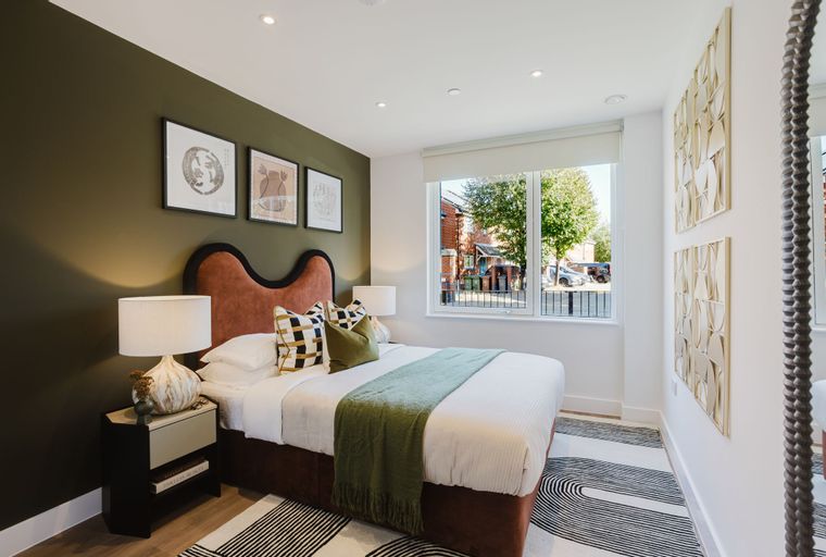 A bedroom with a bed, nightstand, and a window.
