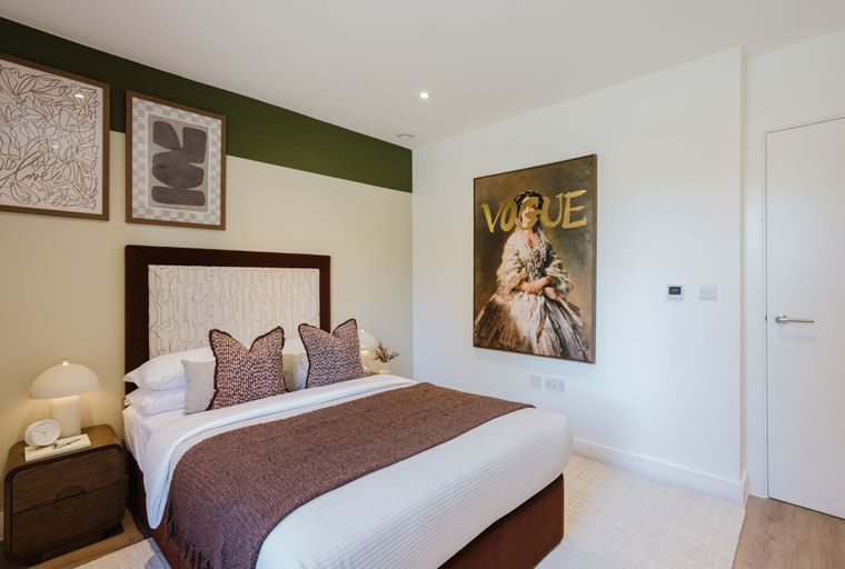 A bedroom with a bed, pillows, a throw, and wall art.