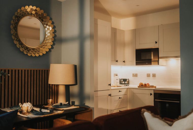 A dining area and kitchen with white cabinets, a toaster, and a mirror.
