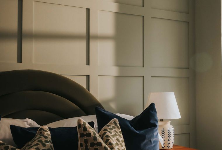 A bedroom with a bed, pillows, a nightstand, and a lamp.