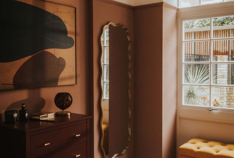 A bedroom with a bed, a dresser, a mirror, and a window.