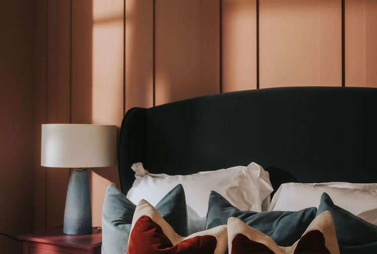 A bedroom with a bed, pillows, and a lamp.
