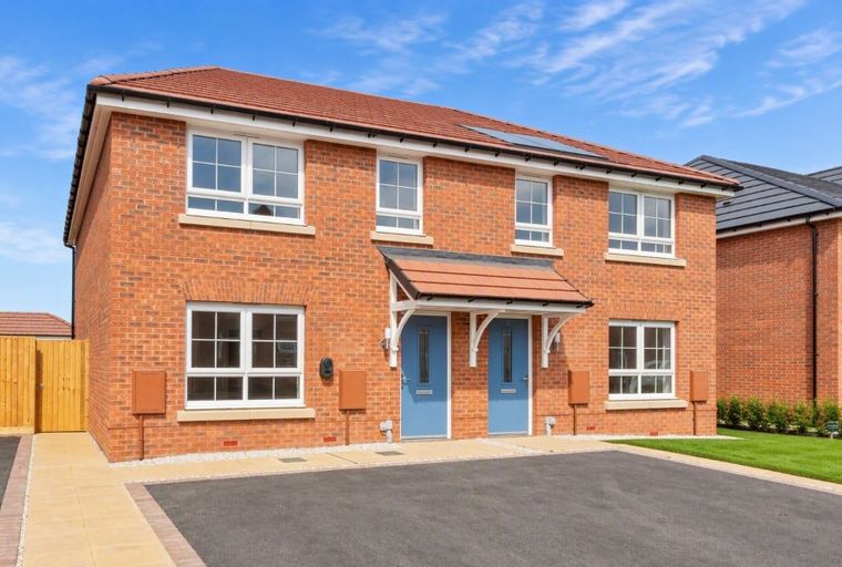 A red brick house with two blue front doors and white-framed windows.