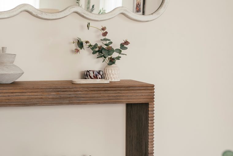 A console table with a mirror above it and two baskets below.