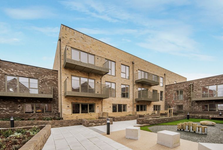 A courtyard of a modern apartment building with balconies, brick facades, and landscaped areas.