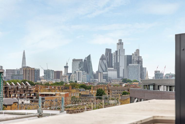 A cityscape with modern skyscrapers and older buildings under a cloudy sky.