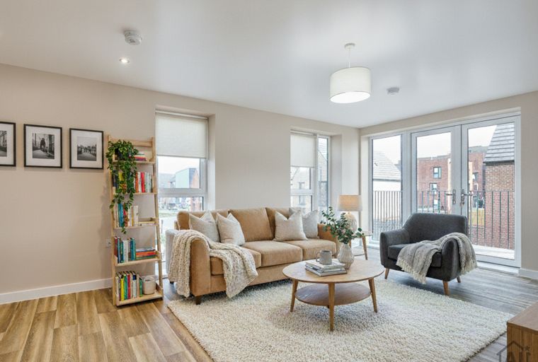 A living room with a sofa, armchair, coffee table, and bookshelf.