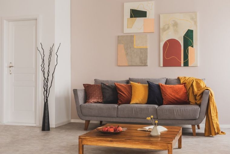 A living room with a gray sofa, colorful pillows, abstract art, and a wooden coffee table.