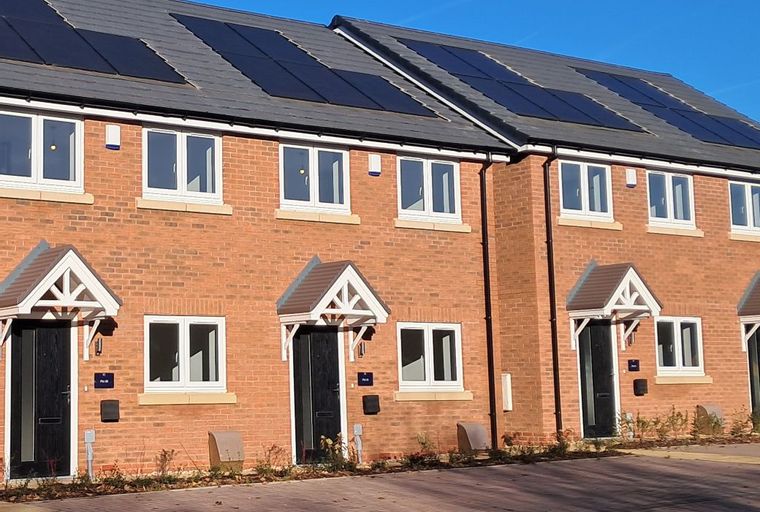 A row of modern brick townhouses with solar panels on the roof.
