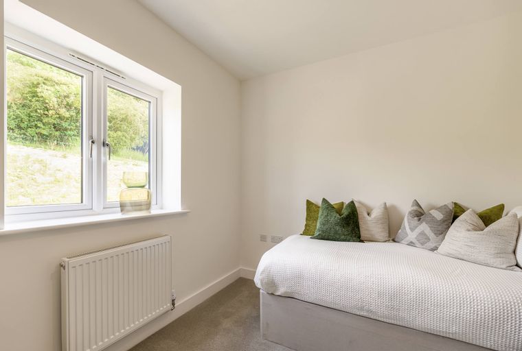 A bedroom with a bed, pillows, and a window.