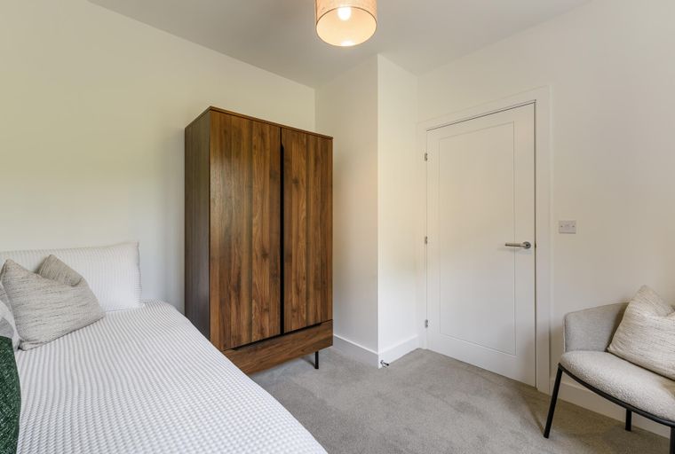 A bedroom with a bed, a wardrobe, and a chair.