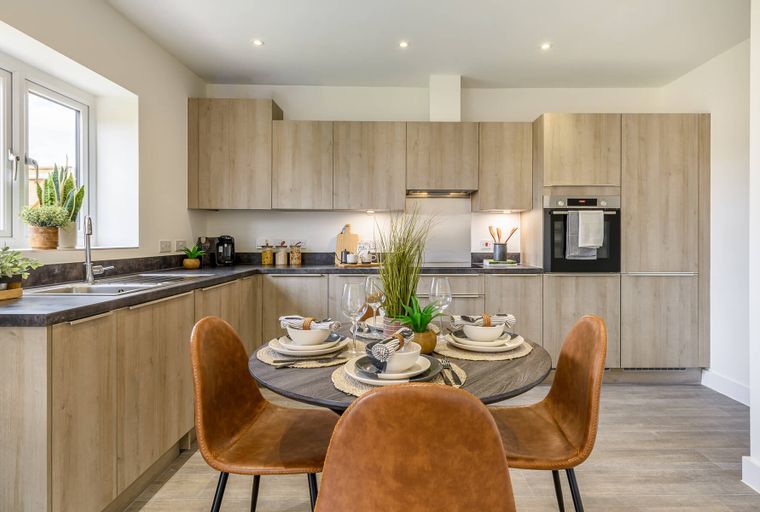 A kitchen and dining area with a round table set for a meal.