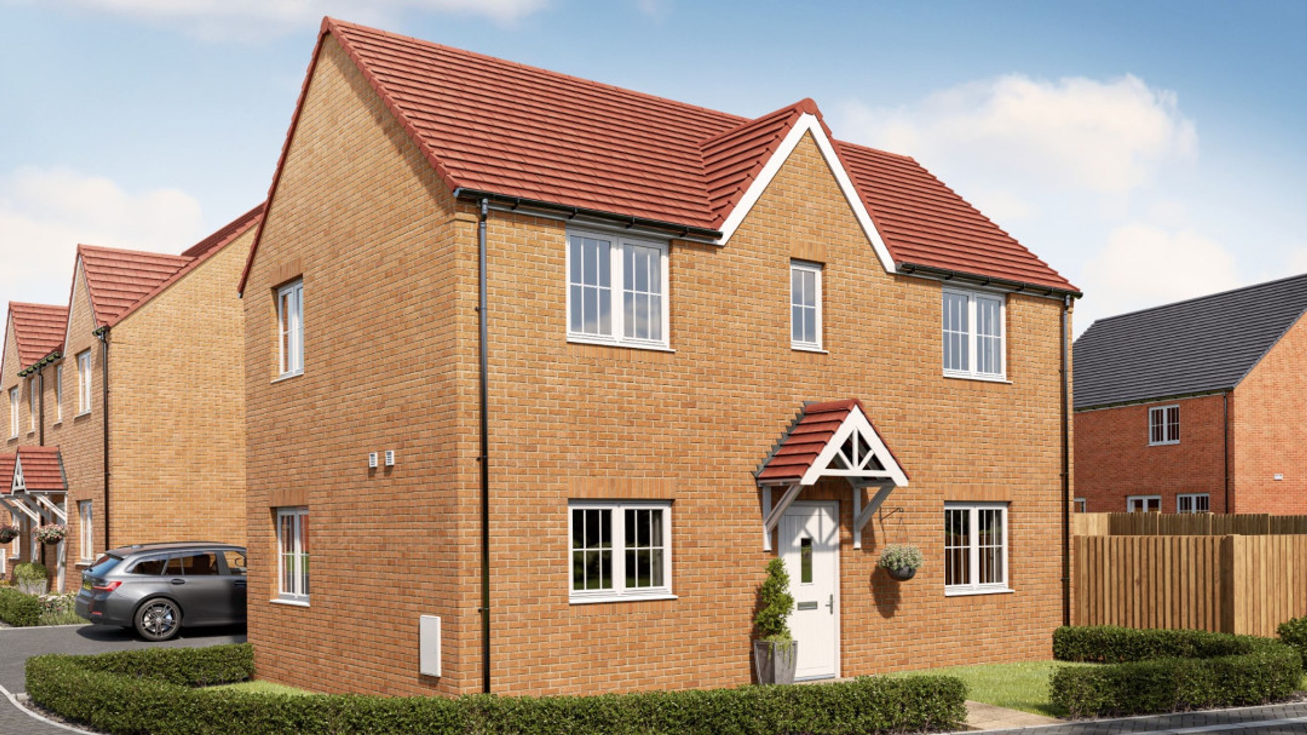 A row of new brick houses with red tile roofs under a blue sky.