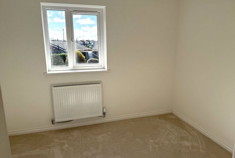 A bedroom with a window and a radiator.