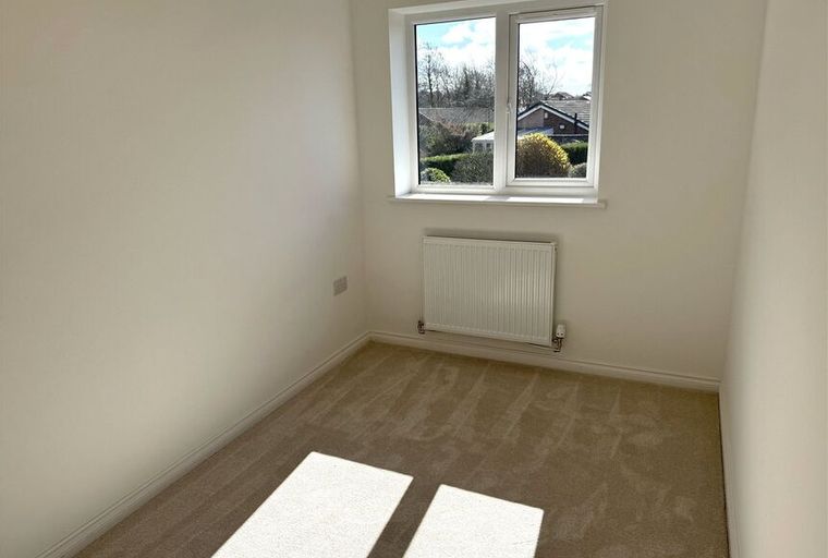 A bedroom with a window and a radiator.