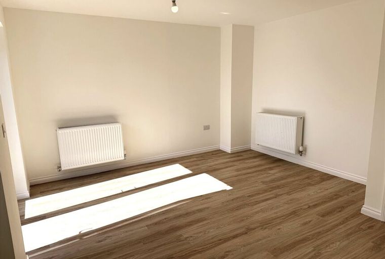 A room with two radiators and wood-effect flooring.