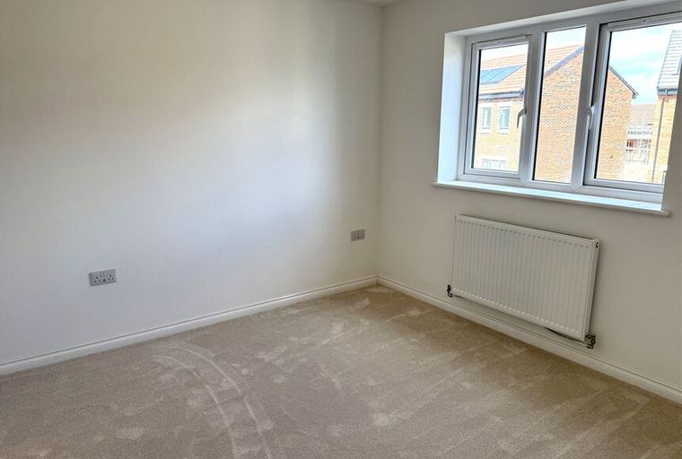 A bedroom with a window and a radiator.
