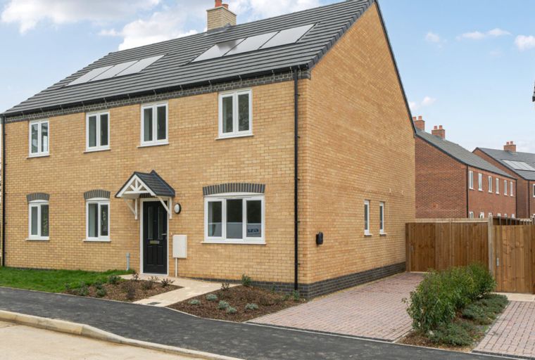 A yellow brick house with a grey roof and solar panels.