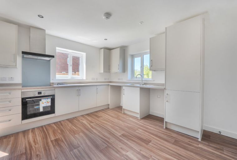A modern kitchen with white cabinets, a built-in oven, and a sink.