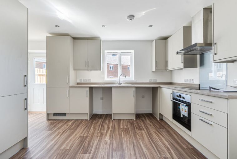 A modern kitchen with cream cabinets, a sink, and a window.