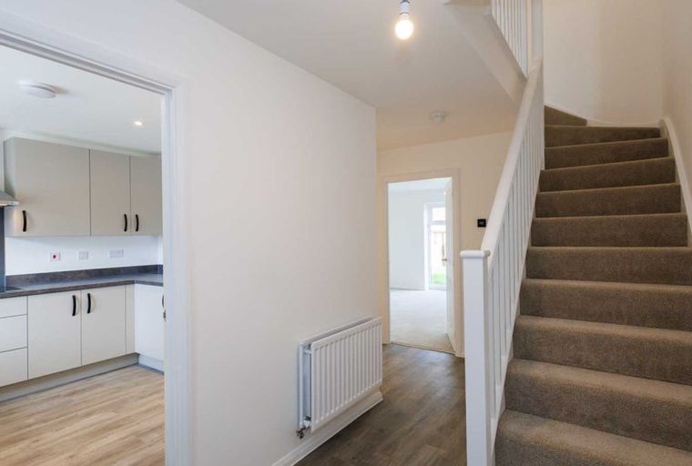 A hallway with a kitchen entrance and a staircase.