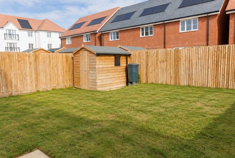 A backyard with a wooden shed, a water butt, and a wooden fence.