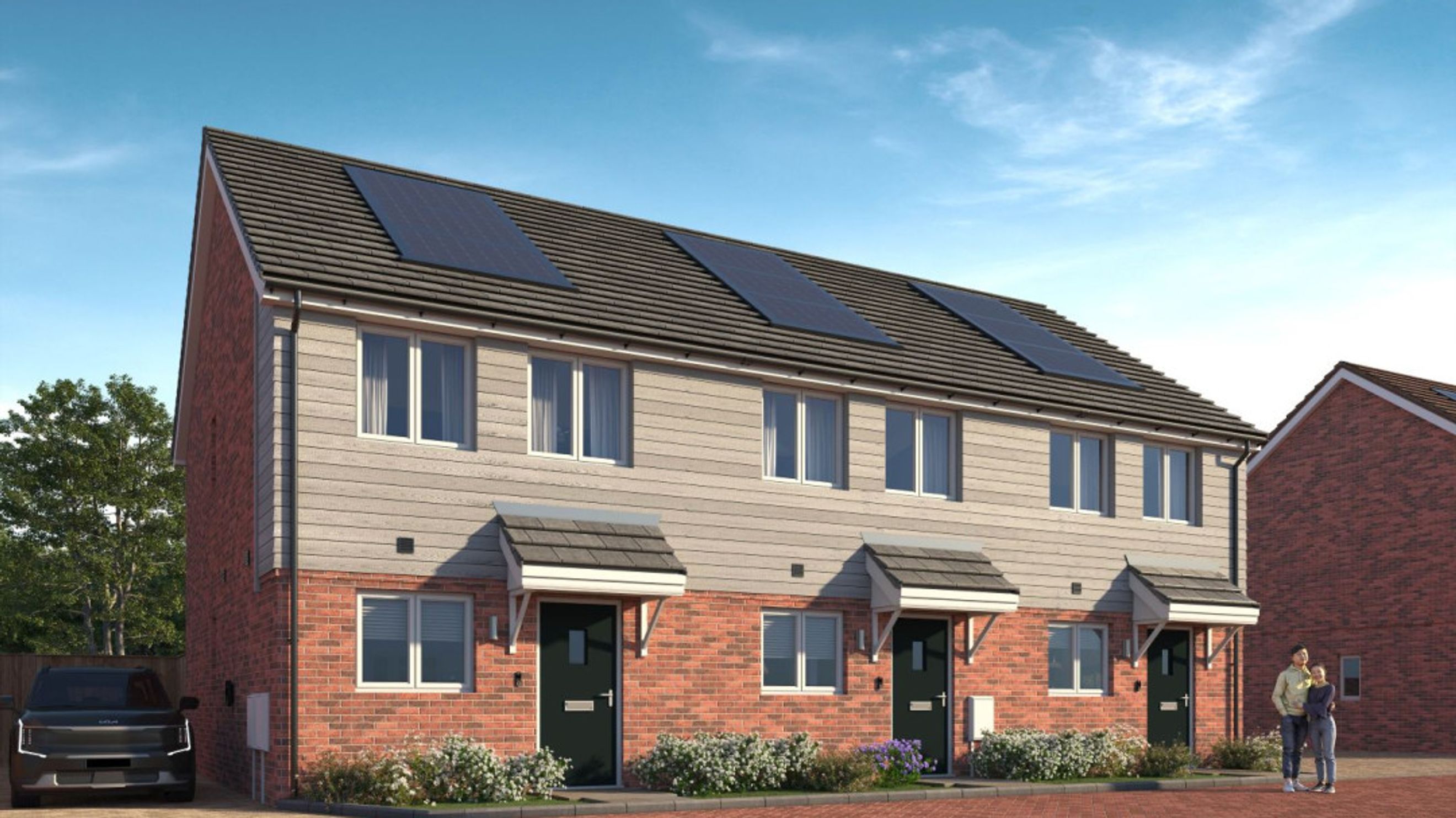 A row of modern townhouses with brick and siding exteriors, solar panels on the roof, and a couple standing outside.