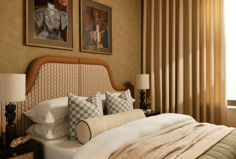 A bedroom with a bed, headboard, pillows, and bedside lamps.