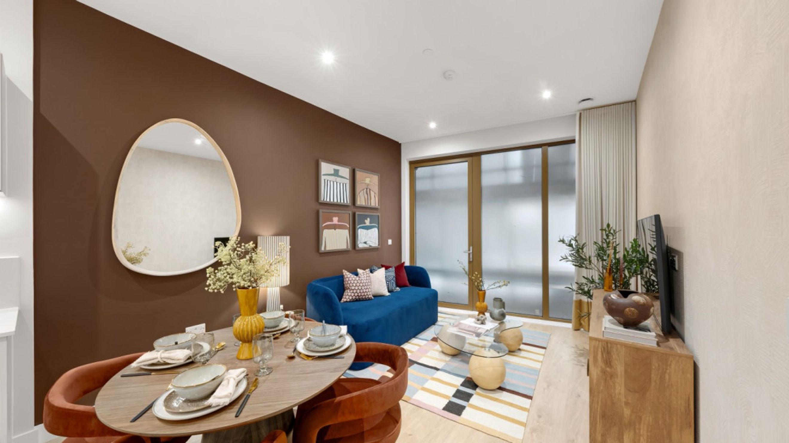 A dining area and living room with a blue sofa, dining table, and a television.