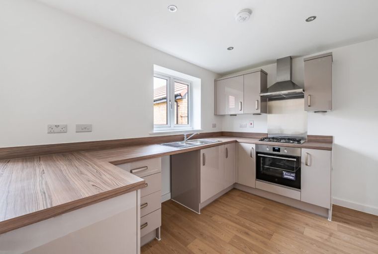 A modern kitchen with light-colored cabinets, a gas hob, oven, and sink.
