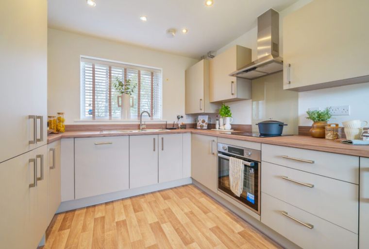 A modern kitchen with cream cabinets, a sink, and an oven.