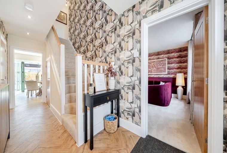 A hallway with a staircase, a console table, and an open doorway to a living room.