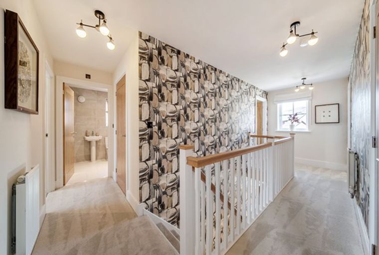 A hallway with a staircase, wallpaper, and doors.