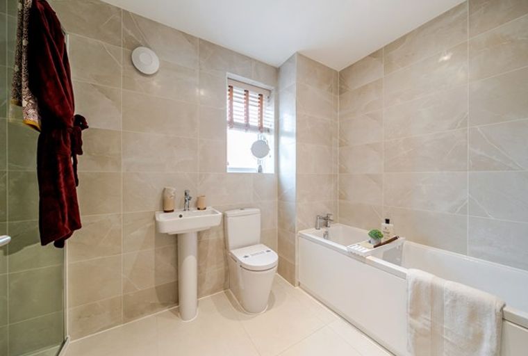 A bathroom with a bathtub, toilet, sink, and a robe hanging on the wall.