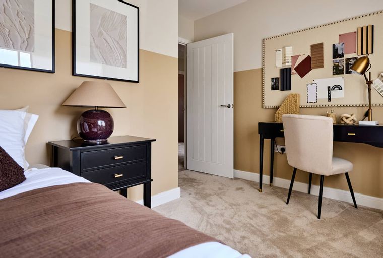 A bedroom with a bed, nightstand, lamp, desk, and chair.