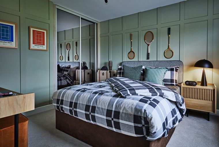 A bedroom with a bed, rackets on the wall, and a bedside table.