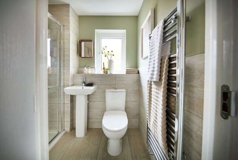 A bathroom with a sink, toilet, shower, and a heated towel rack.