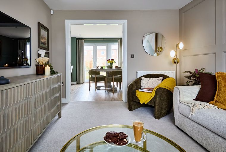 A living room with a sideboard, armchair, and a view into a dining room.