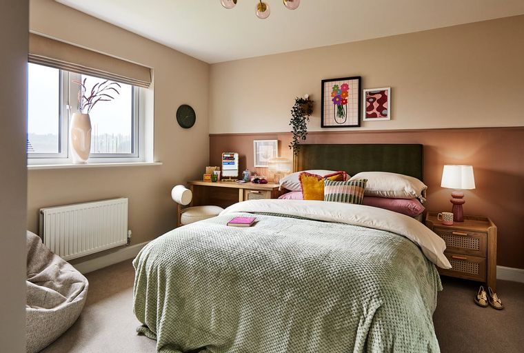 A bedroom with a bed, desk, and window.