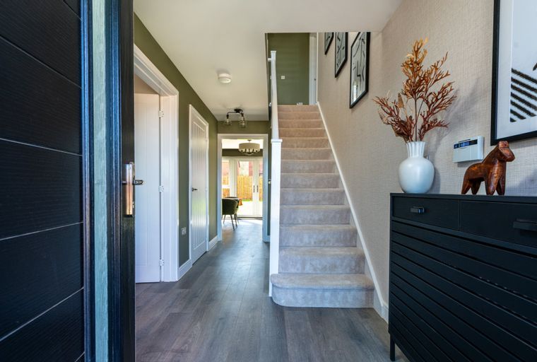 A hallway with a staircase, doors, and a console table.