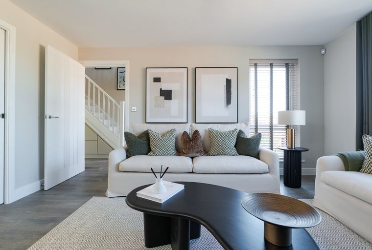 A living room with a white sofa, throw pillows, abstract art, and a coffee table.