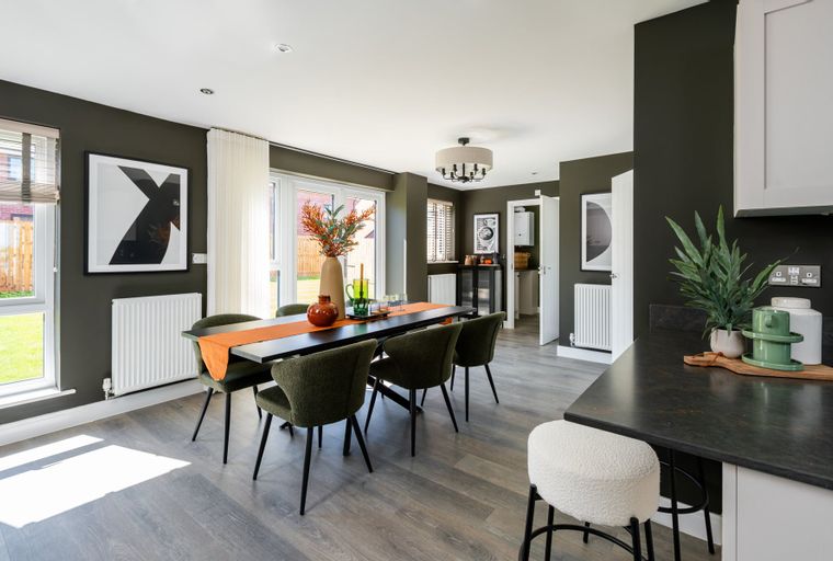 A dining room with a table, chairs, and a vase of flowers.