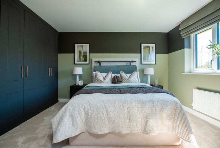 A bedroom with a bed, bedside tables, lamps, a wardrobe, and a window.