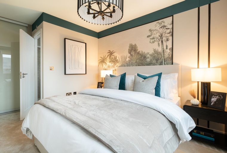 A bedroom with a bed, pillows, lamps, and a mural on the wall.