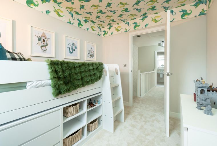 A children's bedroom with a loft bed, dragon-themed wallpaper, and storage.