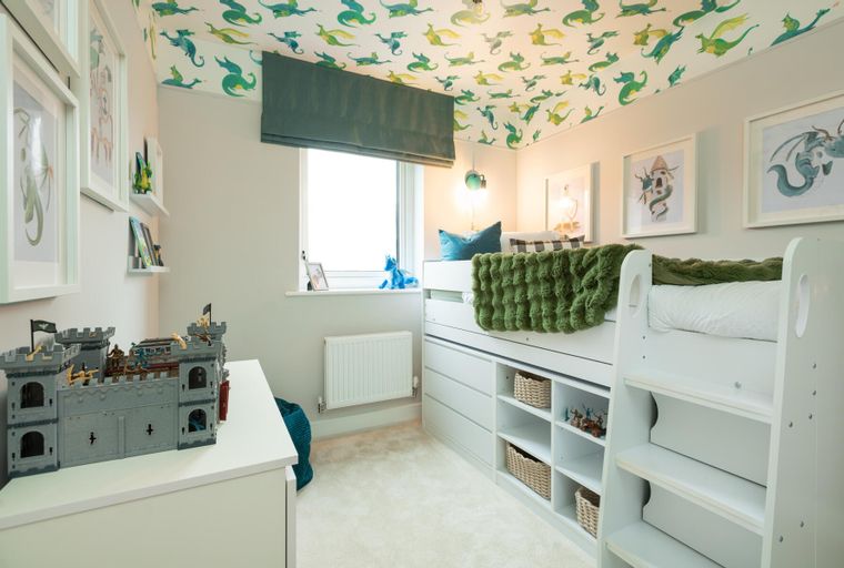 A children's bedroom with a loft bed, dragon wallpaper, and toy castle.
