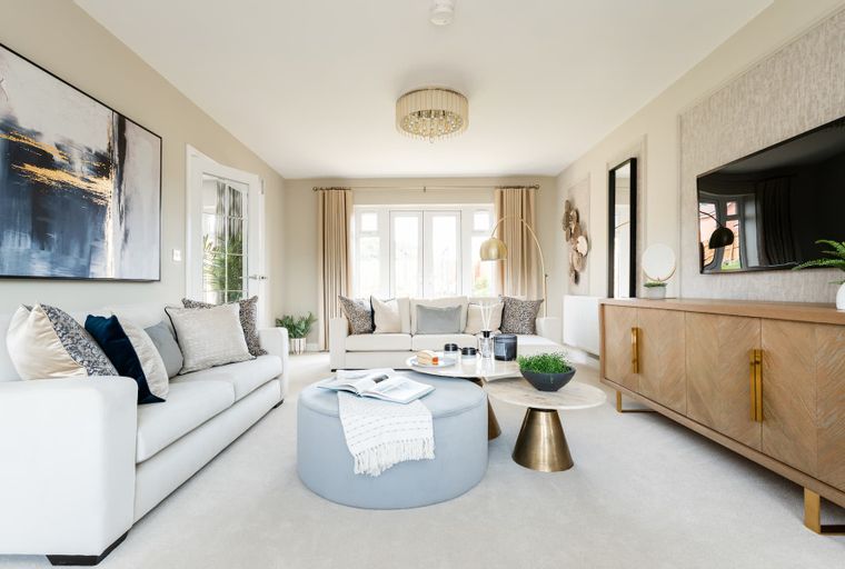 A living room with a white sofa, an ottoman, coffee tables, and a television.