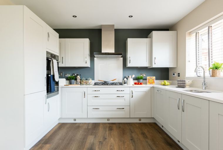 A modern kitchen with white cabinets, a gas stove, and a sink.