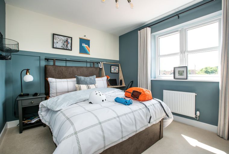 A bedroom with a bed, a desk, and a window.