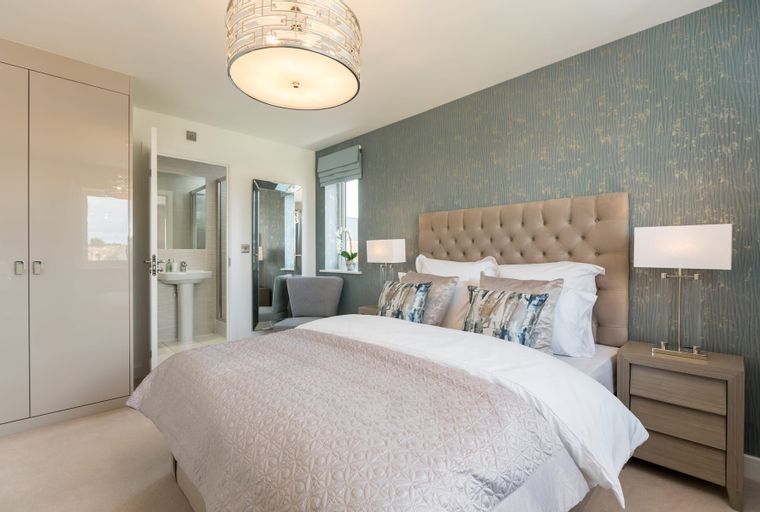 A bedroom with a bed, bedside tables, a wardrobe, and an en-suite bathroom.